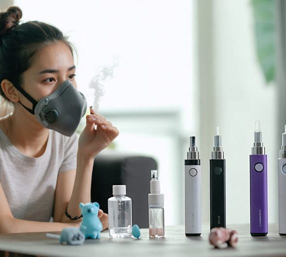 A concerned young mother holding a protective mask while examining vaping devices on a table, reflecting on indoor air quality and family health.